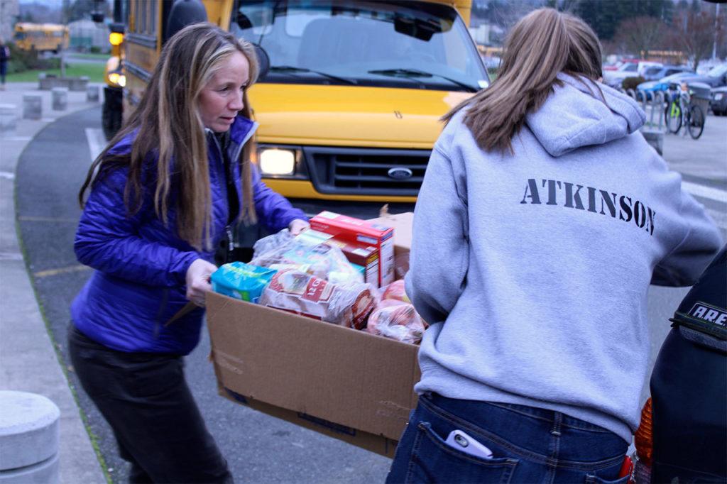 Granite Falls High School staff member Jackie Woolman-Morgan and Food Drive Coordinator Lindsey Atkinson load food and gifts in vehicles for personal delivery to families. (Contributed photo)

