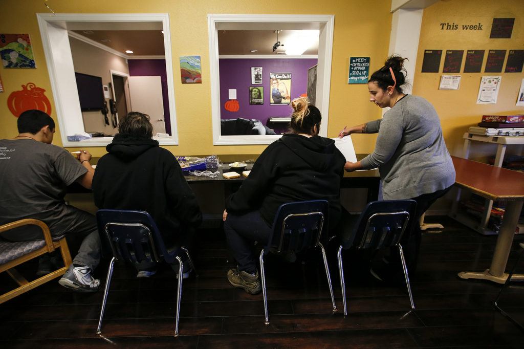 Cocoon House advocate Morgan Huber (right) talks with teens gathered at the nonprofit’s U-Turn drop-in center on Broadway in Everett on Tuesday, Dec. 13. (Ian Terry / The Herald)
