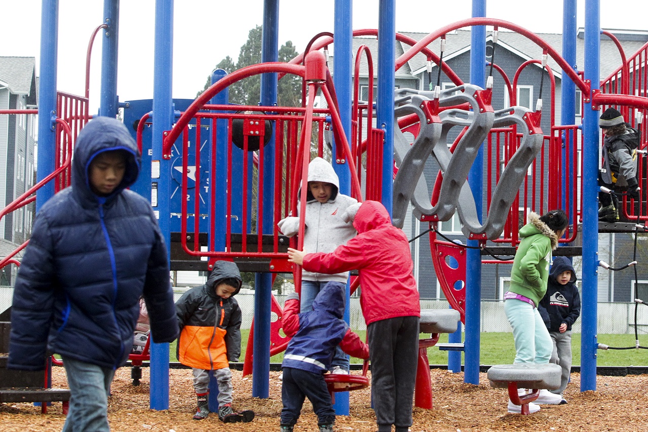 Kids play on Hawthorne Elementary School’s new playground that opened Saturday afternoon in Everett. (Ian Terry / The Herald)
