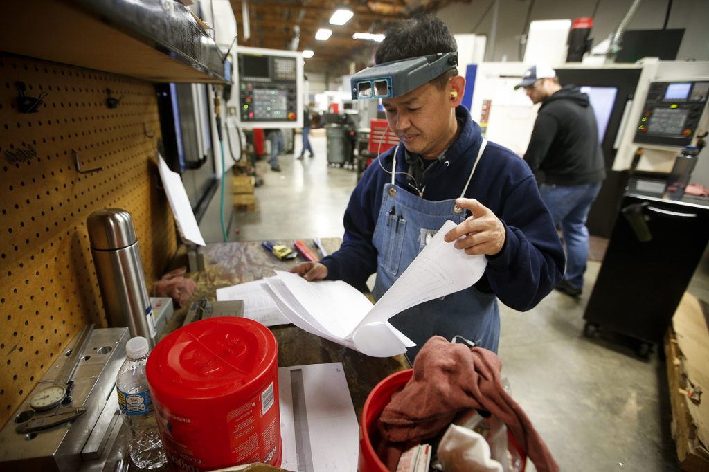 Heng Hun looks through notes while working at RB Enterprises in Mukilteo on Wednesday. Hun has worked at RB Enterprises for five years and has been a machinist for almost 15 years. (Ian Terry / The Herald)
