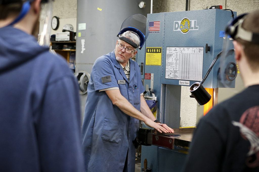 Instructor Ron Fronheiser talks with students before they get started working with a band saw at the Washington Aerospace Training & Research Center at Paine Field in Everett on Dec. 16. (Ian Terry / The Herald)
