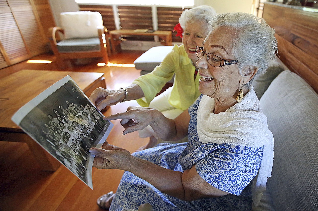 In this Nov. 18 photo, Joan Martin Rodby (left) and Emma Veary look at their fifth-grade class photo during a reunion in Makawao, Hawaii. Rodby remembered the carefree walks to school, and her family building an air raid shelter in their yard. Veary reminisced about her days singing, and when her family covered the windows at night so Japanese pilots couldn’t use the light of homes to guide them. (AP Photo/Rick Bowmer)
