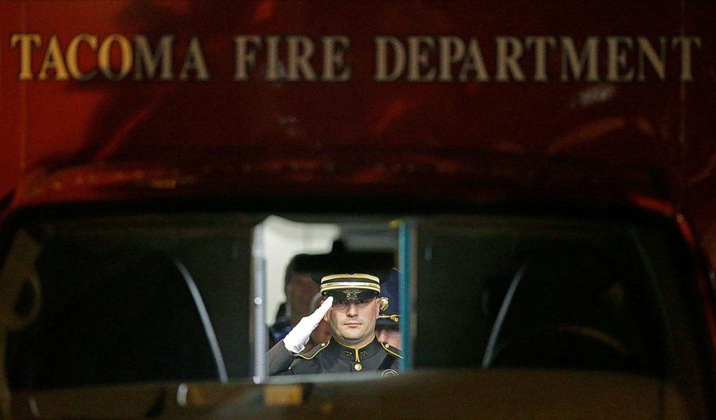 A law enforcement officer salutes as viewed through the windshield of a Tacoma Fire Department ambulance as the body of officer Reginald “Jake” Gutierrez is placed in the vehicle for a procession away from Tacoma General Hospital, in Tacoma. (AP Photo/Ted S. Warren)
