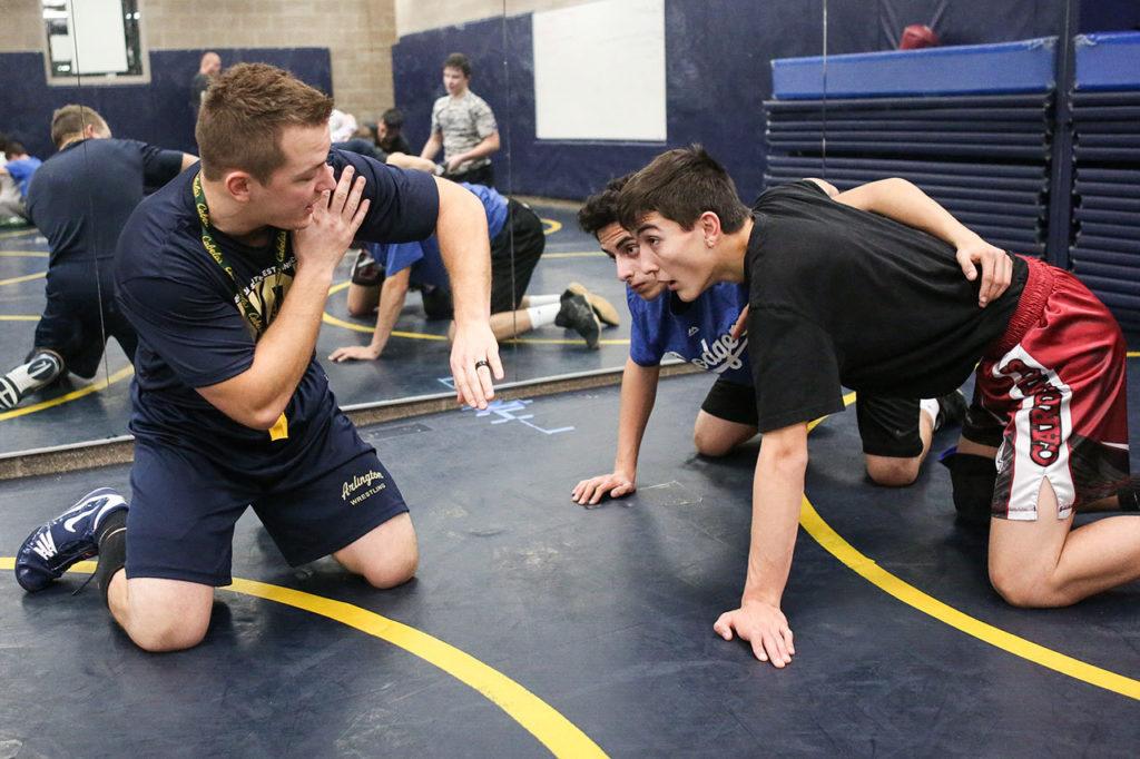 New Arlington wrestling coach Jonny Gilbertson instructs Pedro Sanchez (center) and Patrick Connelly during practice Wednesday. (Kevin Clark/The Herald)
