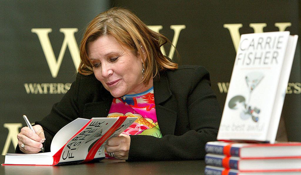 In this Feb. 20, 2004 photo, author Carrie Fisher autographs her new book “The Best Awful” at a promotional event in London. (AP Photo/John D. McHugh, File)
