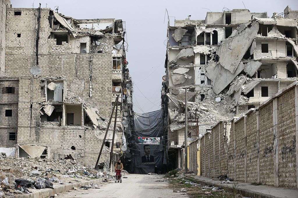 In this Dec. 5 photo, A Syrian man pushes a baby stroller as he walks past anti-sniper curtains remaining in a street in Aleppo, Syria. Aleppo shakes with explosions and gunfire day and night in both the government and rebel sides. (AP Photo/Hassan Ammar)
