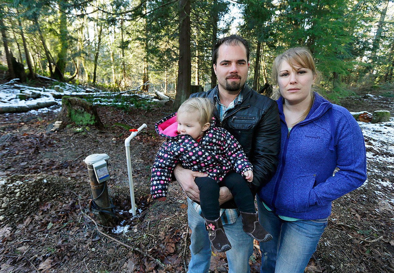 Bud Breakey and his wife, Deborah, pose for a photo with their daughter, 15-month-old Kaylin, by the well they paid to drill on property they own near Bellingham on Dec. 6. (AP Photo/Ted S. Warren)