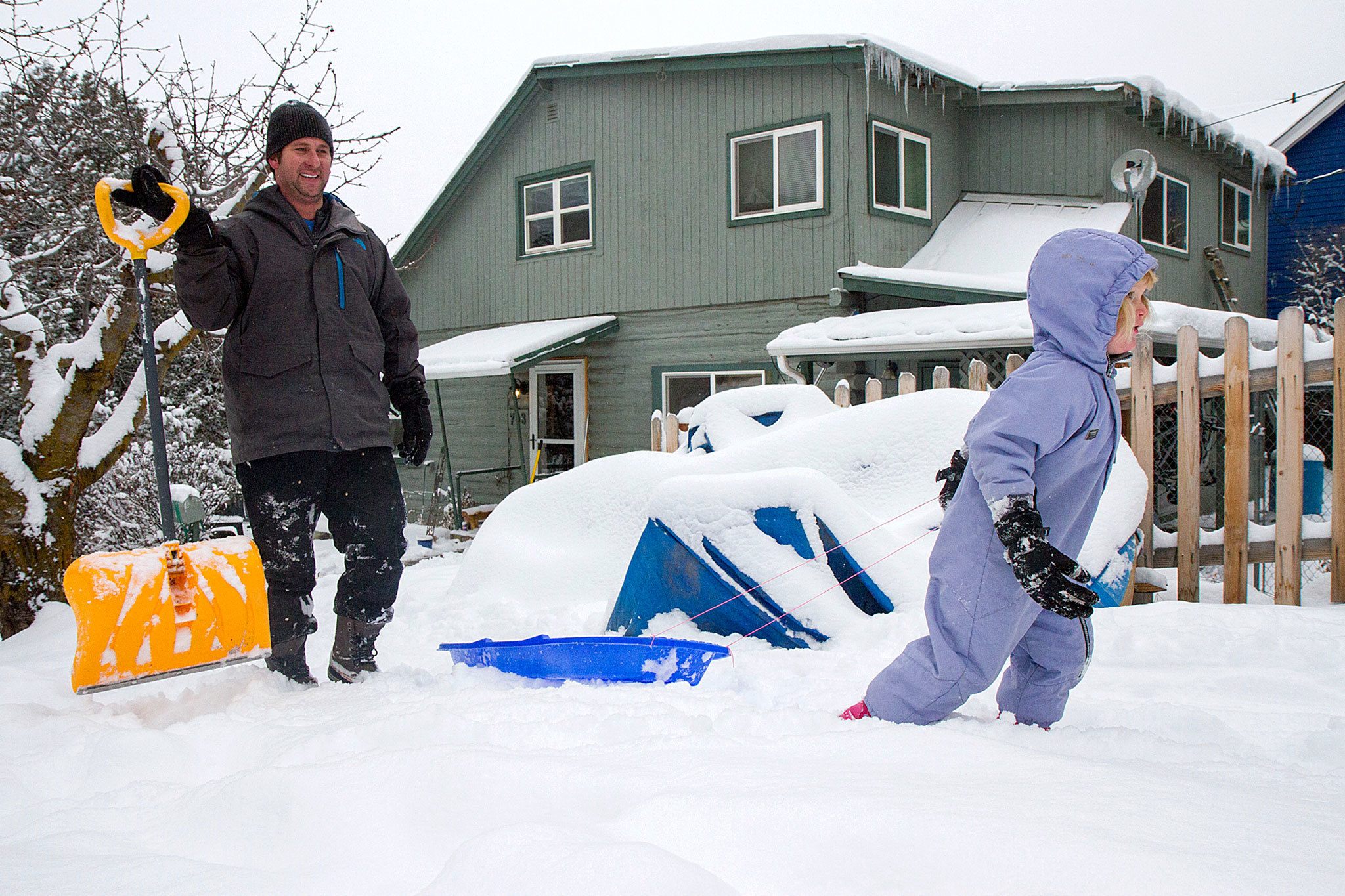 Leila Power, 3, pulls her sleigh up the hill as her dad, Sean, shovels the sidewalk and street to try and keep up with heavy snowfall in Glenwood Springs, Colorado, on Thursday. (Chelsea Self/Glenwood Springs Post Independent)