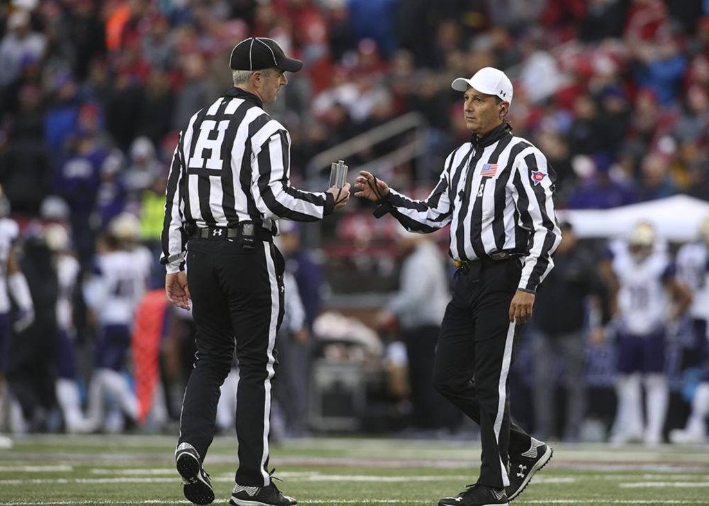 A referee hands over a flask to another referee after the object was thrown on to the field at the Apple Cup on Nov. 25, 2016, in Pullman. (AndyBronson / The Herald)
