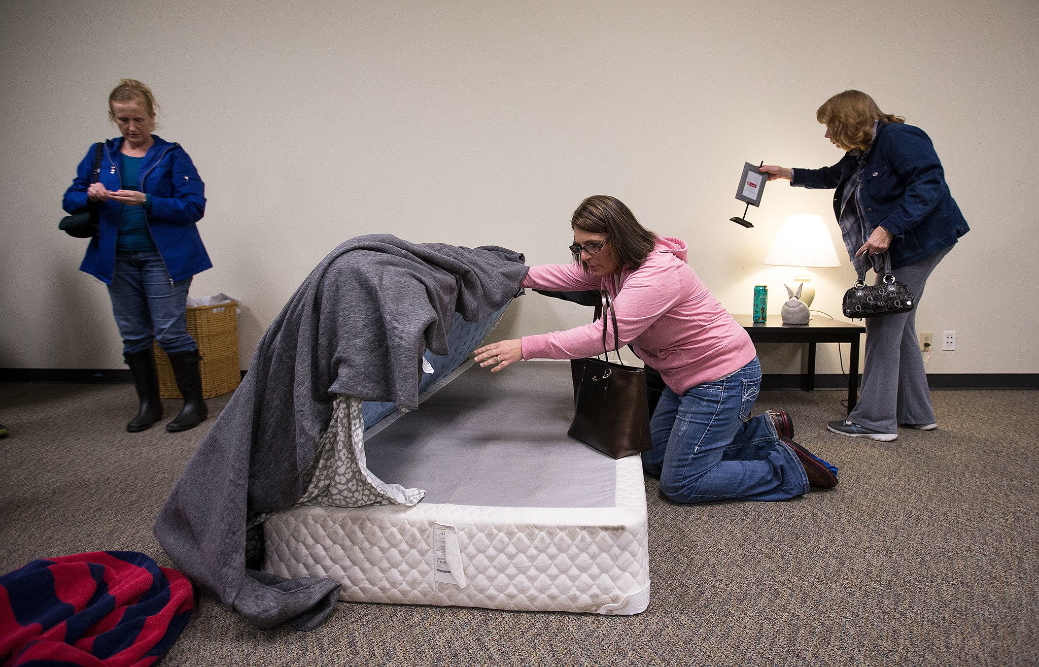 Tracy Van Beek lifts up a bed as she and other parents look for hidden drugs in a model girl’s bedroom at Weston High on Thursday, Jan. 19, in Arlington. Van Beek and other parents and kids attended the “Not in My House!” event, put on by the Arlington Drug Awareness Coalition. (Andy Bronson / The Herald)