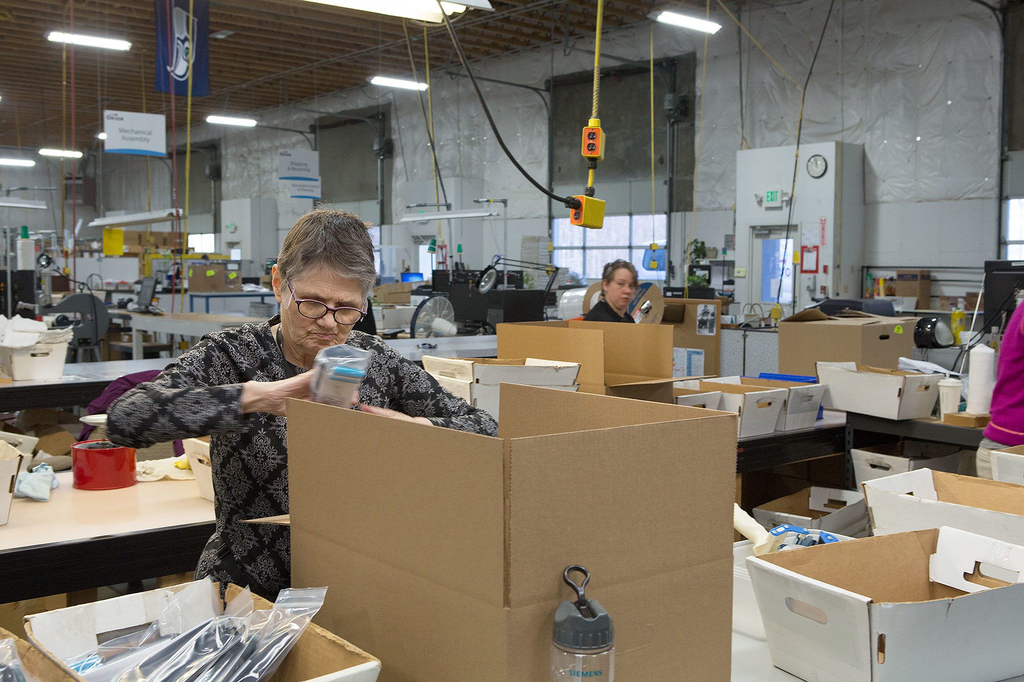 Caroline Powers and Amy Tibet (right) work at Orion Industries, a nonprofit that combines commercial work with a social mission, on Dec. 20 in Mukilteo. (Andy Bronson / The Herald)