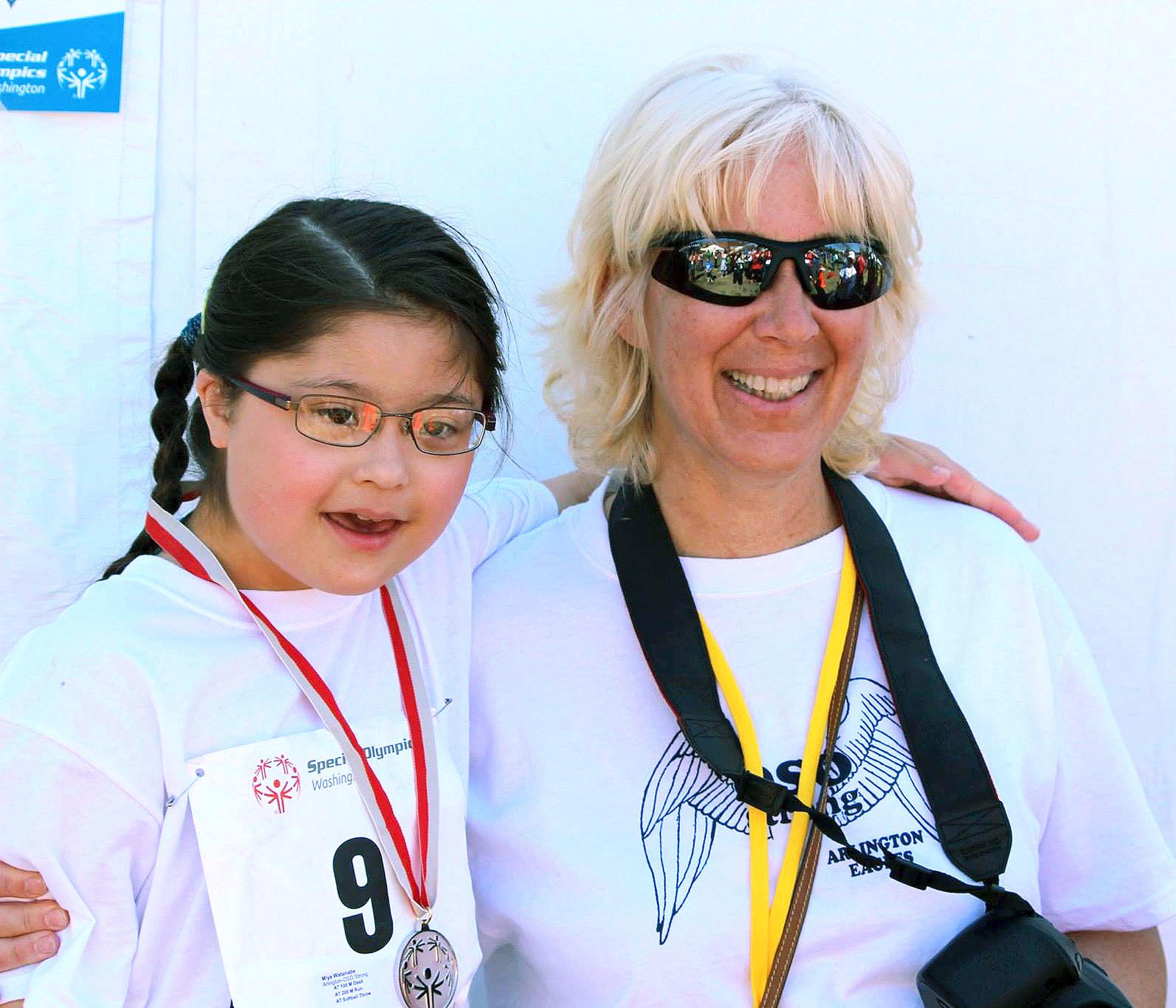 Arlington Eagles coach Sandy Catiis (right) and 8-year-old Miya Watanabe of Arlington pose together after Watanabe won a silver medal in the 200-meter dash in a Special Olympics competition in 2014. (Photo courtesy of Sandy Catiis)