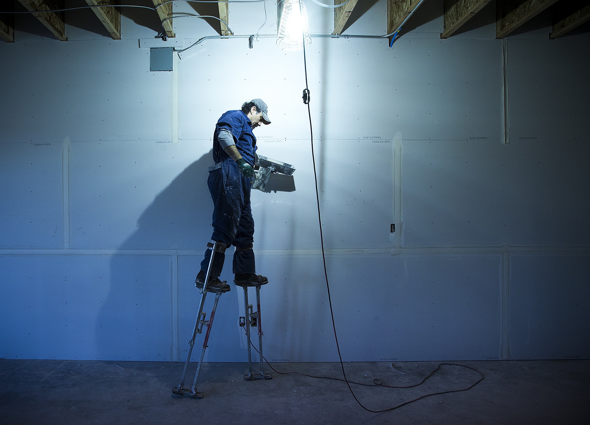 Tony Perez uses stilts to finish work high up on a wall in the Arlington Boys and Girls Club’s new teen center on Wednesday. (Ian Terry / The Herald)