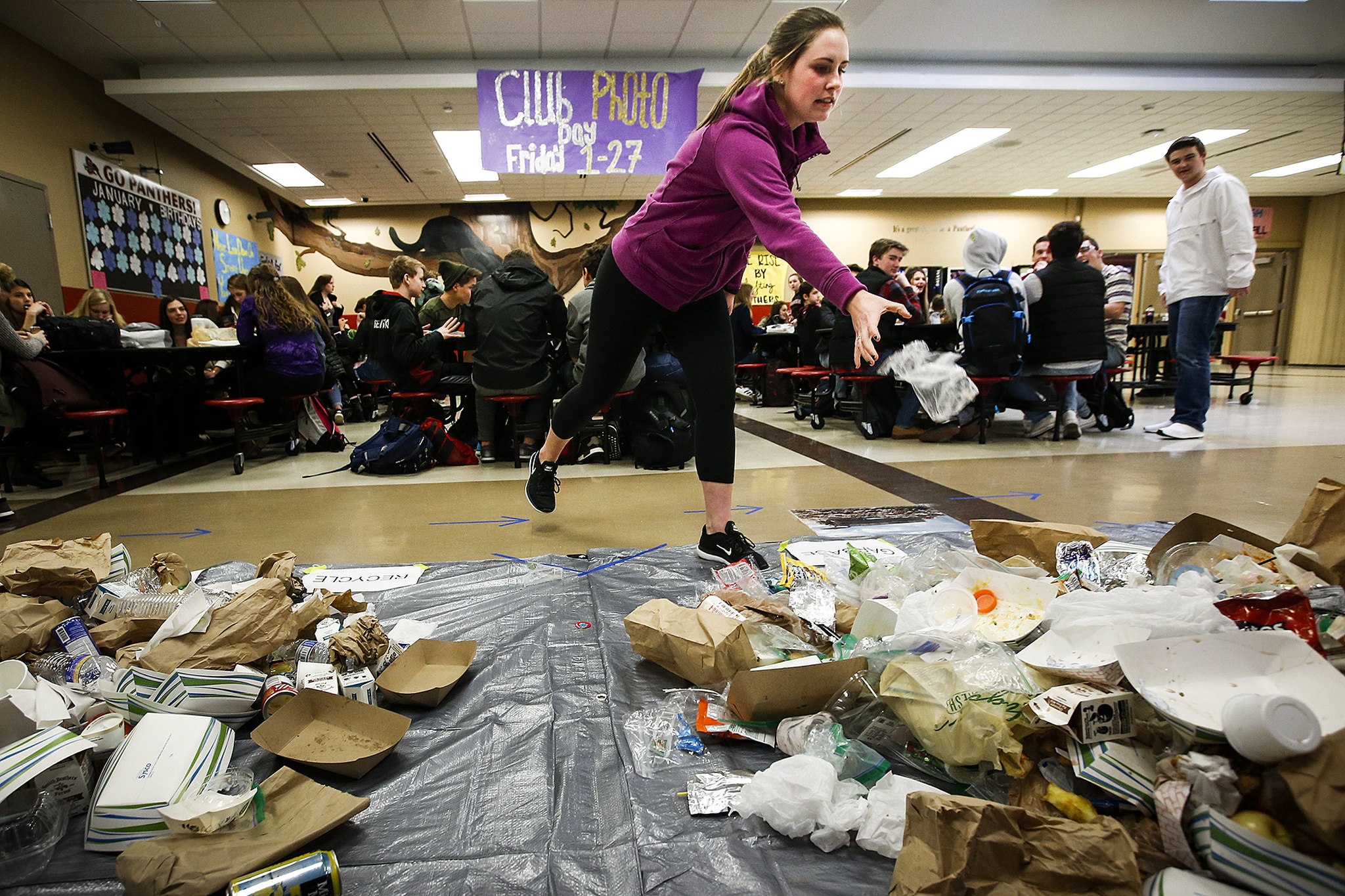 Ame Bridgman, a senior at Snohomish High School, tosses a piece of waste into a pile on the school’s cafeteria floor during Waste Managementճ Trash on a Tarp initiative Tuesday. The program, which marked its first event in Snohomish County on Tuesday, aims to help students visualize the amount of trash created by daily activities. According to Waste Management, Snohomish County produces just under 3 million pounds of trash each day, about a third of which could have been recycled. (Ian Terry / The Herald)