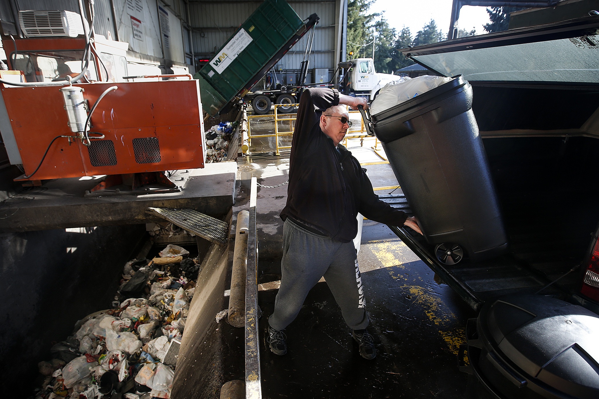 Scott Reed, of Stanwood, hoists a container of garbage out of his truck at the North County Transfer Station in Arlington on Thursday. The station collects, processes and offloads approximately 335 tons of waste each day. (Ian Terry / The Herald)