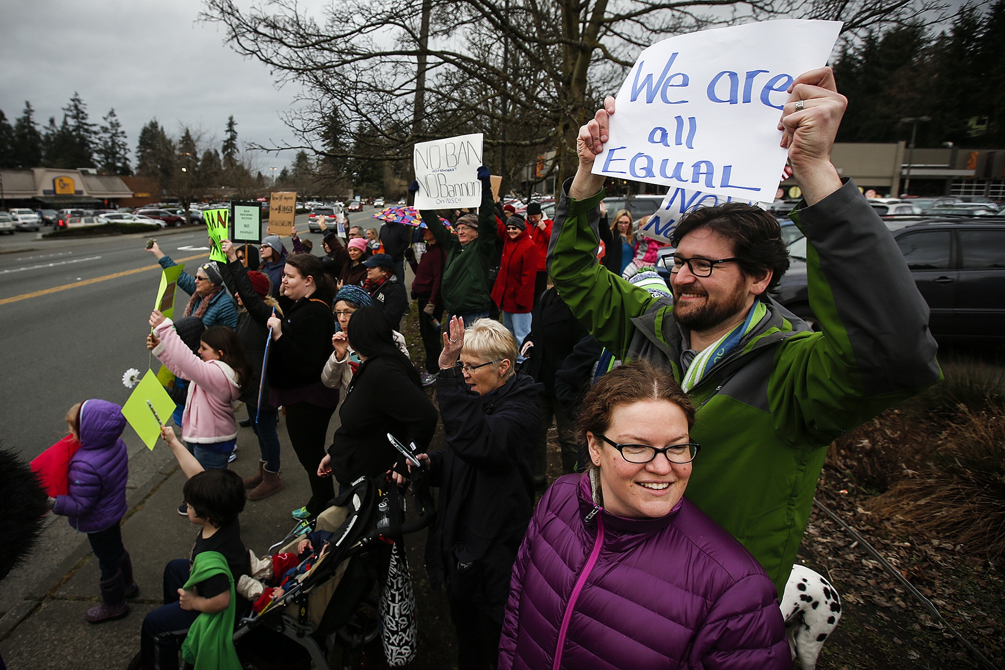 Marty Ross (right) and Leah Ross (center right), of Lake Forest Park, stand at the corner of 100th Avenue West and Edmonds Way during a gathering in Edmonds on Sunday, Jan. 29. The protest aimed to raise awareness and voice opposition to President Trump’s executive order banning immigrants from seven Muslim-majority countries from entering the U.S. The executive order, signed on Friday, triggered massive protests at airports across the country as details came out about refugees and other visitors being detained despite having all documents necessary for entry into the U.S. (Ian Terry / The Herald)