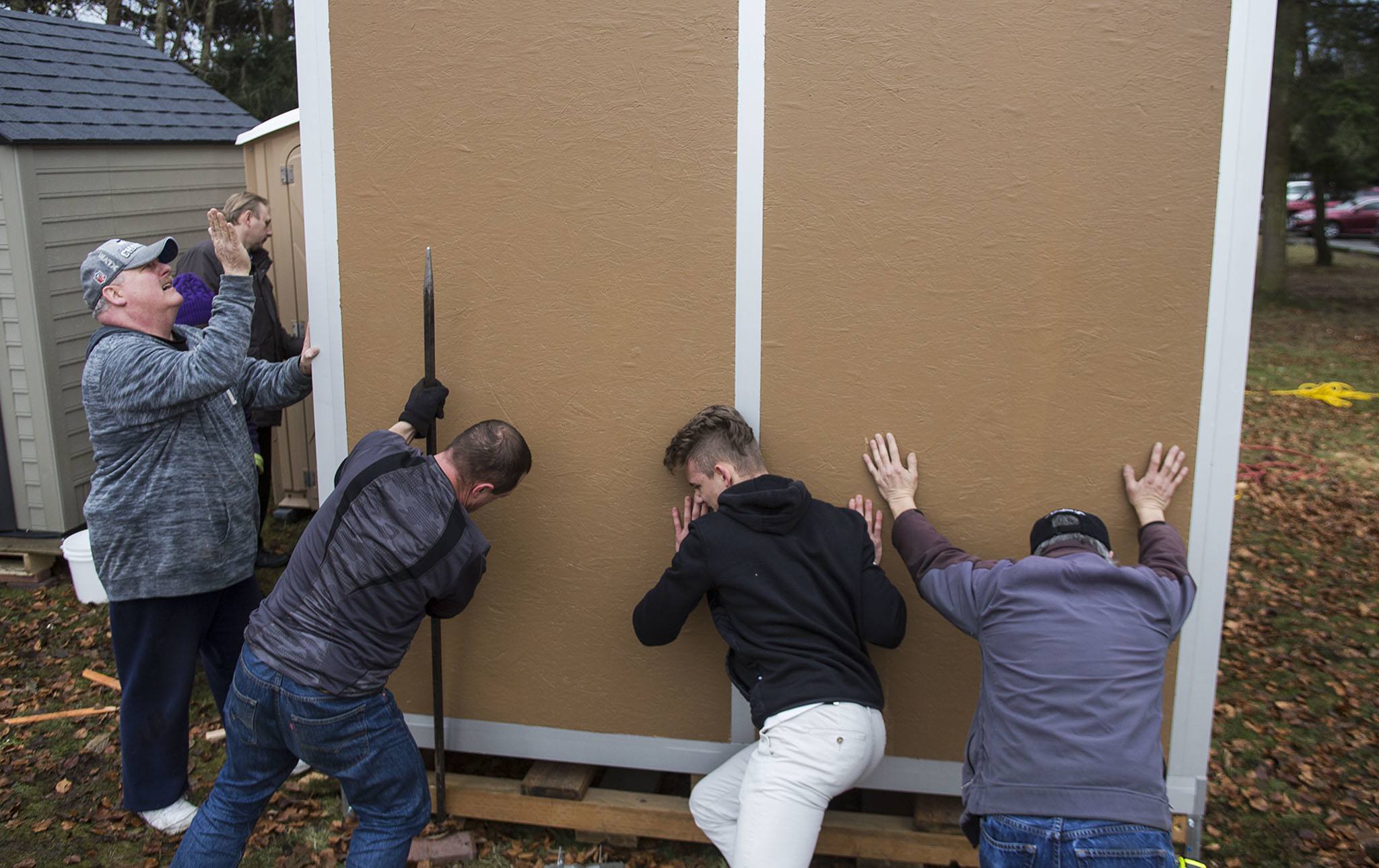 Darrel Potter (left) guides Gary Michaels, David Musiyenko and Tony Thompson as they push the community living room into place at the new tent village for homeless students at Good Shepherd Baptist Church on Jan. 17, in Lynnwood. Michaels attends Edmonds Community College and is the first resident to live on the site. (Daniella Beccaria / The Herald)