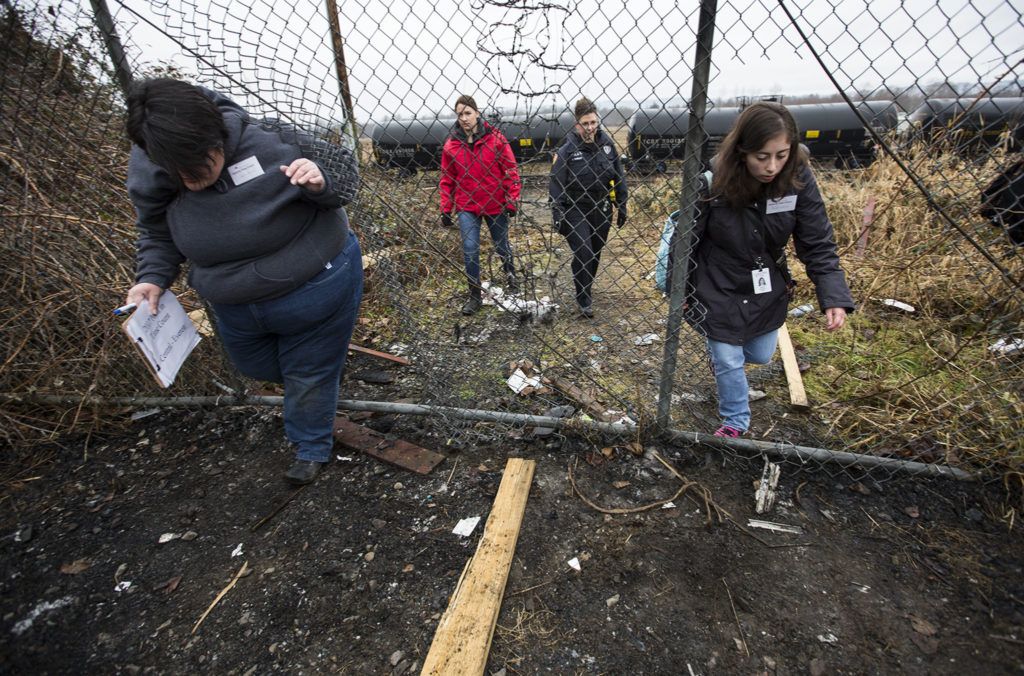 Gretchen Holtz (left) and Autumn Manning (right), both volunteers from Compass Health, leave the train tracks through holes in a fence with Officer Inci Yukurt and law enforcement social worker Kaitlyn Dowd after finding an empty camp during the annual Point in Time Homeless Count on Tuesday. (Daniella Beccaria / The Herald)
