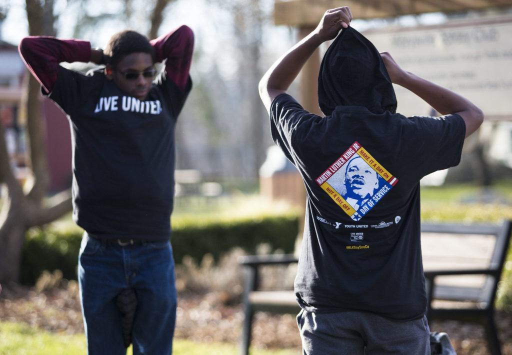 Isaiah Williams, 12, (right) from the YMCA My Achiever Program, puts on a shirt commemorating Martin Luther King Jr. during a service day in recognition of MLK Day at Jennings Park on Monday in Marysville. (Daniella Beccaria / The Herald)
