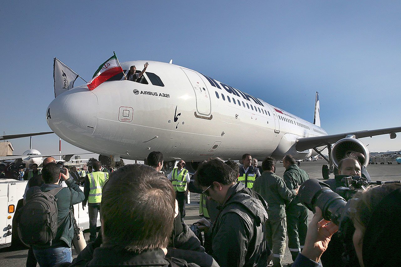 The pilot of Iran Air’s new Airbus plane waves with an Iranian flag after landing at Mehrabad airport, in Tehran, Iran, on Thursday, Jan. 12. The first of 100 Airbus planes that Iran is expected to receive after its historic nuclear deal with world powers ended some sanctions landed on Thursday in the capital, Tehran. (AP Photo/Vahid Salemi)