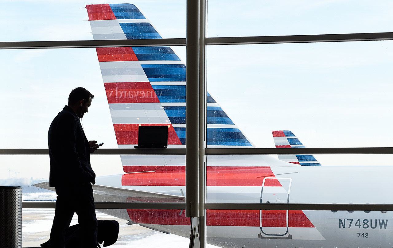 A passenger talks on the phone as American Airlines jets sit parked at their gates at Washington’s Ronald Reagan National Airport in 2016. (AP Photo/Susan Walsh)