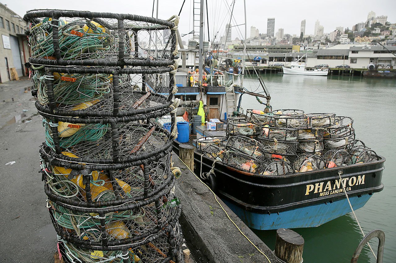 Crab pots sit on a processing pier and the back of a boat Tuesday at Fisherman’s Wharf in San Francisco. (AP Photo/Eric Risberg)