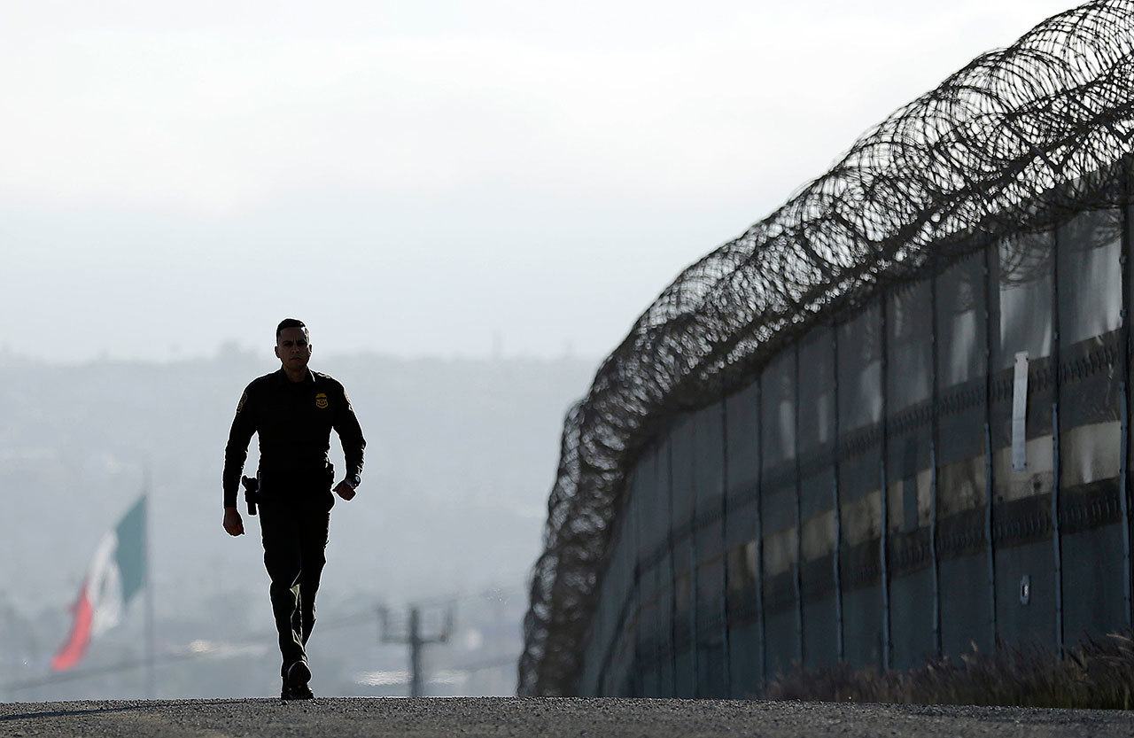 A Border Patrol agent walks near a fence separating Tijuana, Mexico, and San Diego in June. (AP Photo/Gregory Bull, file)