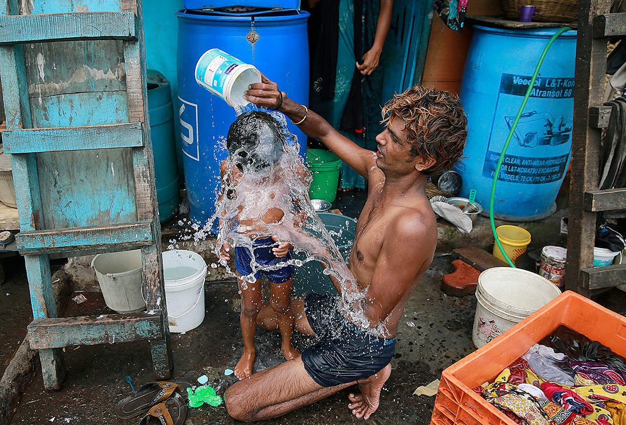 In this May 23, 2016 photo, a man bathes his son on a hot afternoon in a slum in Mumbai, India. For the third straight year, Earth set a record for the hottest year, NOAA and NASA announced. (AP Photo/Rafiq Maqbool, File)