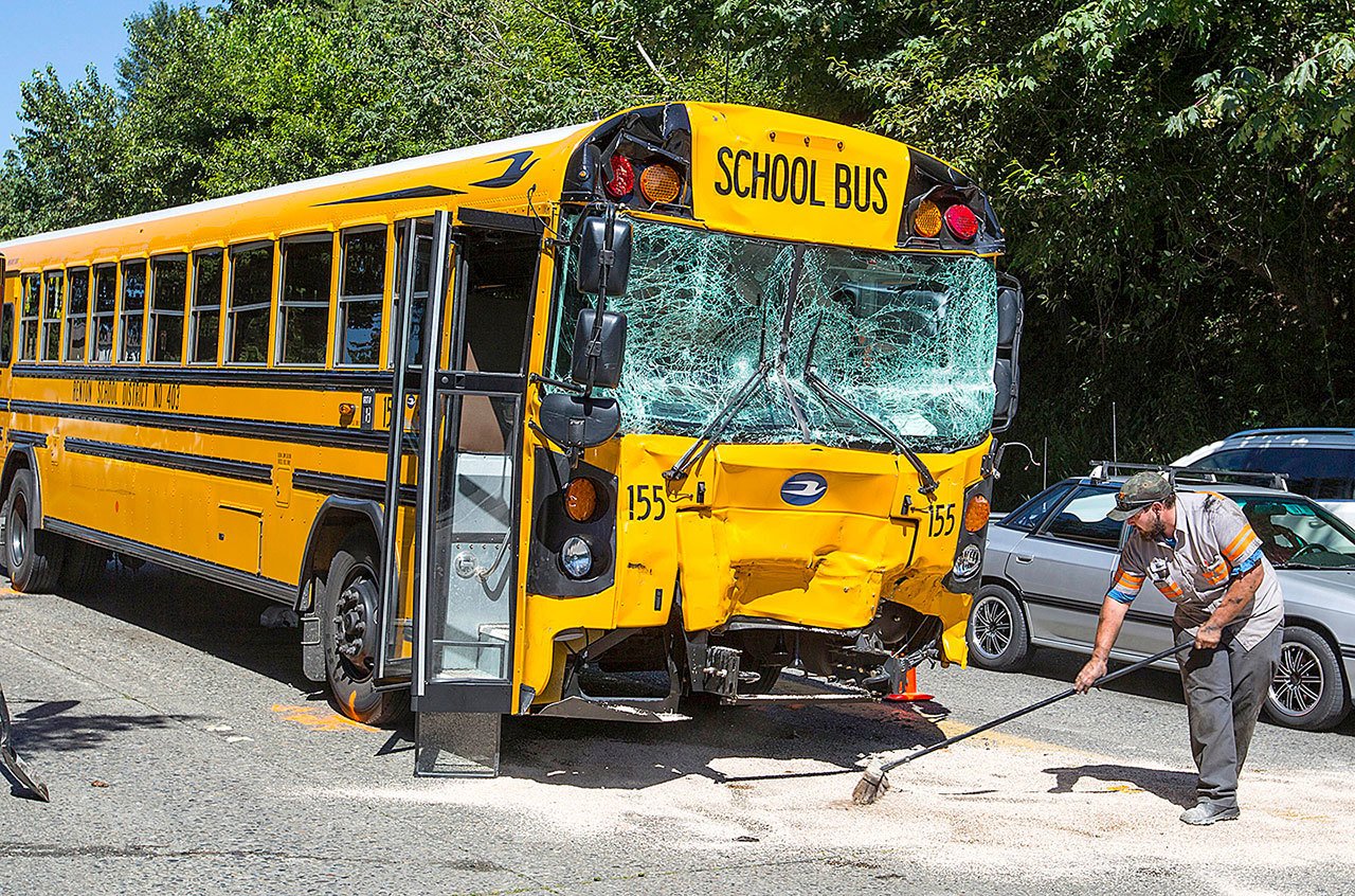In this June 3, 2016 photo, a worker sweeps a material at the scene of a school bus collision, in Renton. A bill that would require school buses to have seat belts is being considered by lawmakers in Washington. (Mike Siegel/The Seattle Times via AP, File)