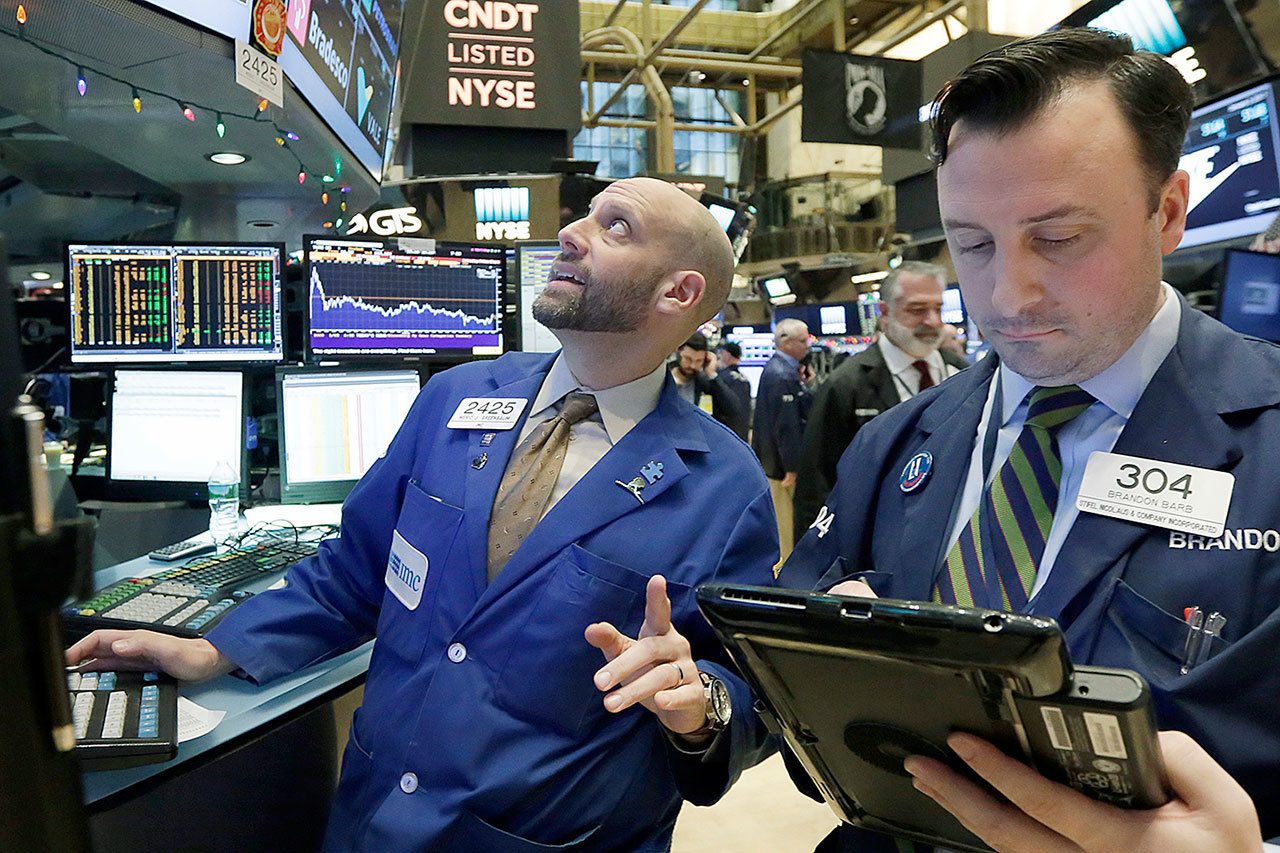 Specialist Meric Greenbaum (left) works at his post on the floor of the New York Stock Exchange on Tuesday, Jan. 3. The stock market opened the year on a strong note, led by big gains in banks and energy companies. (AP Photo/Richard Drew))