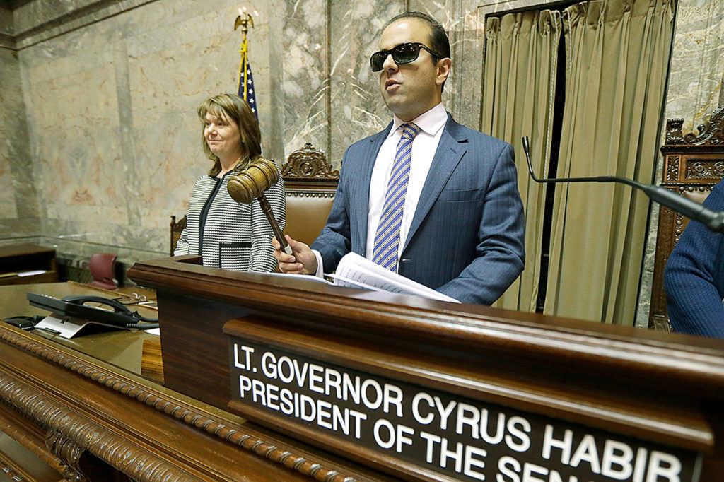 Washington Lt. Gov.-elect Cyrus Habib holds the gavel as he stands at the Senate chamber dais next to Senate Counsel Jeannie Gorrell on Thursday during a practice session to test technical equipment in Olympia. Habib, who will preside over the Senate, will be Washington’s first blind lieutenant governor, and the Senate has undergone a makeover that incorporates Braille into that chamber’s floor sessions that will allow Habib to know by the touch of his finger which lawmaker is seeking to be recognized to speak. (AP Photo/Ted S. Warren)
