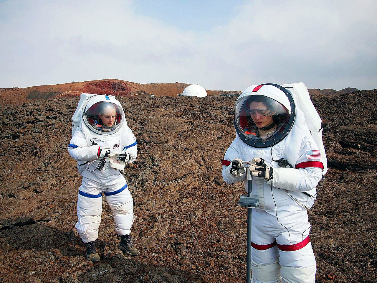 In this May 23, 2014 photo, Lucie Poulet (right) uses a geotechnical tool while Annie Caraccio records the data during a previous study outside the domed structure that will house six researchers for eight months in an environment meant to simulate an expedition to Mars, on Mauna Loa on the Big Island of Hawaii. (Ross Lockwood/University of Hawaii via AP)