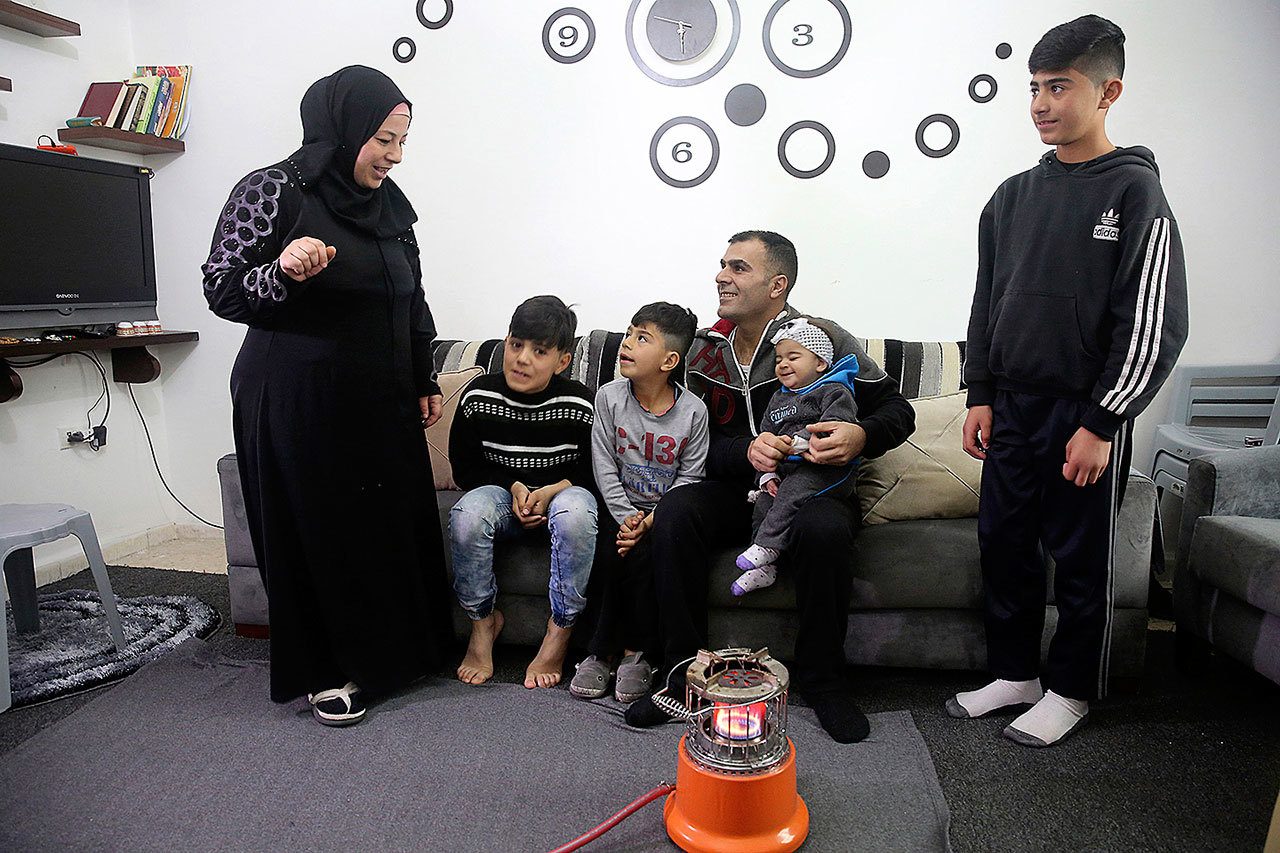 The Sawan family from Moadamiyeh, outside Damascus, talk in front of a gas heater in their home in Amman, Jordan on Saturday, Jan. 28, the day the family learned they won’t be headed to the U.S. after President Donald Trump’s executive order to indefinitely halt all Syrian refugee immigrations. (AP Photo/Sam McNeil)