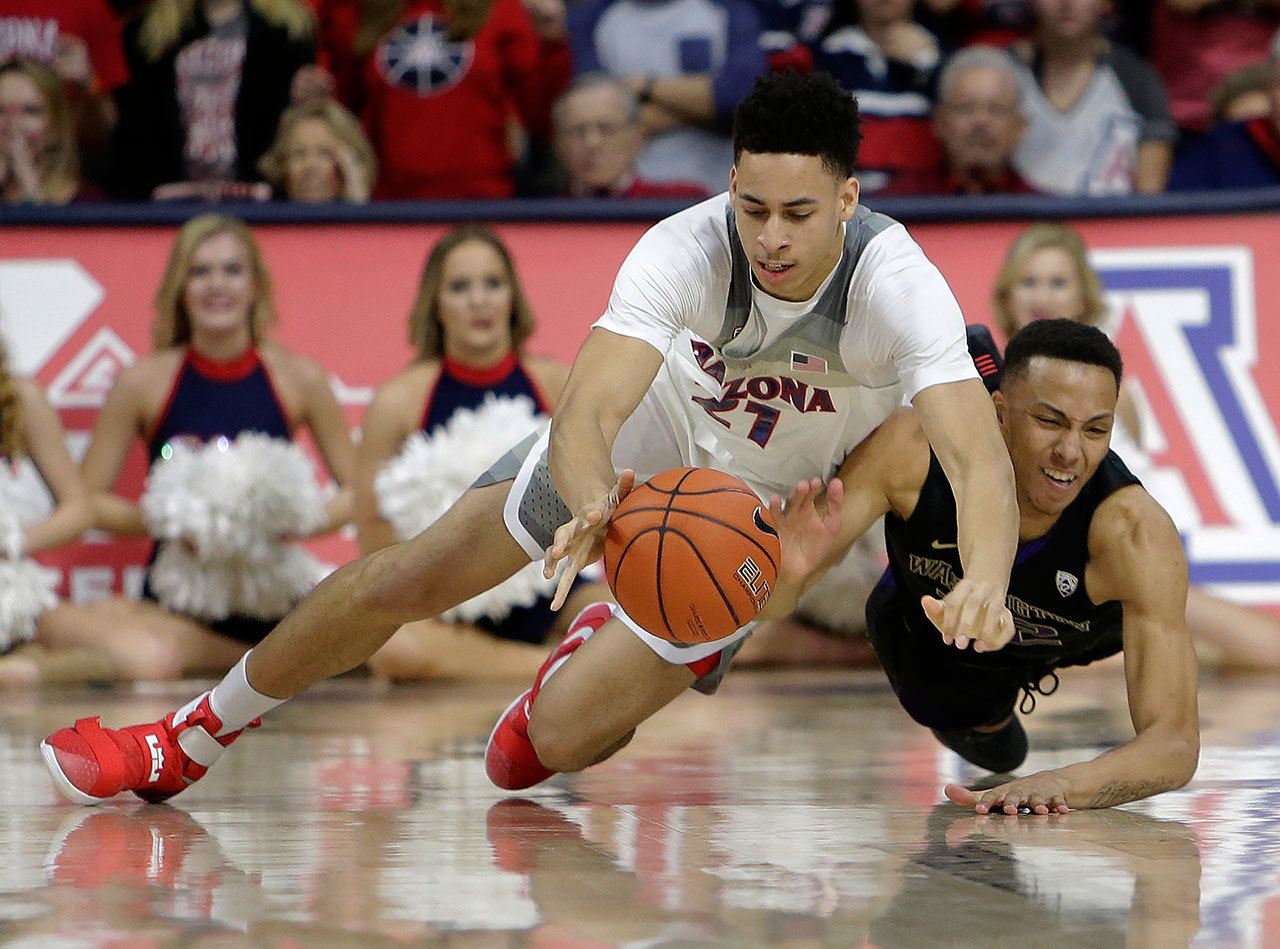 Arizona center Chance Comanche (left) and Washington forward Dominic Green battle for a loose ball during the first half Sunday in Tucson, Arizona. (AP Photo/Rick Scuteri)
