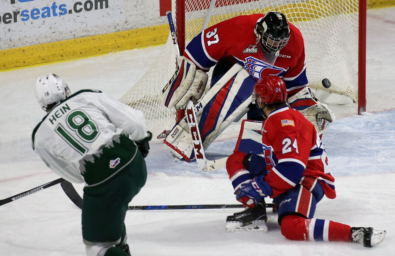 Everett’s Brandson Hein fires a goal past Spokane goalie Dawson Weatherill with Spokane’s Ty Smith (24) looking on during the Silvertips’ 5-0 win over the Chiefs on Wednesday night at Xfinity Arena in Everett. (Kevin Clark / The Herald)