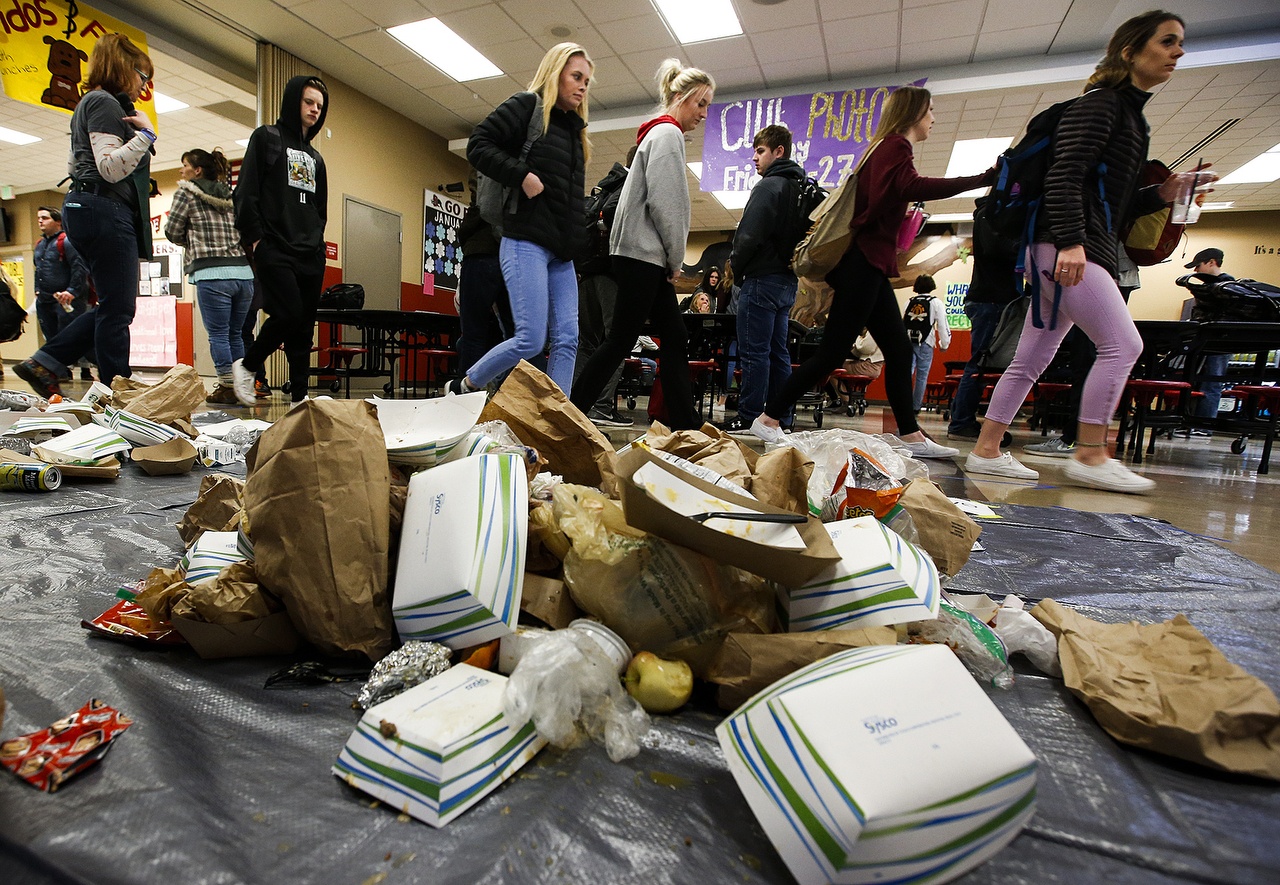 Students at Snohomish High School walk past lunchroom waste piled on the school’s cafeteria floor during Waste Managementճ Trash on a Tarp initiative Tuesday. The program, which marked its first event in Snohomish County on Tuesday, aims to help students visualize the amount of trash created by daily activities. According to Waste Management, Snohomish County produces just under 3 million pounds of trash each day, about a third of which could have been recycled. (Ian Terry / The Herald)
