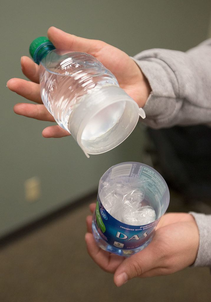 A Dasani water bottle with a hidden compartment in the middle behind the logo is held by a parent during a search for hidden drugs in a model bedroom at Weston High on Thursday, Jan. 19, in Arlington. The “Not in My House!” event was put on by the Arlington Drug Awareness Coalition. (Andy Bronson / The Herald)
