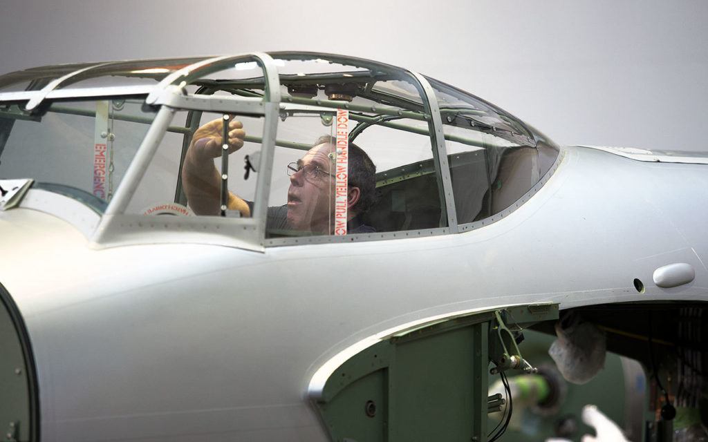 Chris Wood, the Flying Heritage Collection aircraft mechanic, removes the escape hatch in the cockpit of a de Havilland Mosquito, a World War II attack aircraft. (Andy Bronson / The Herald)
