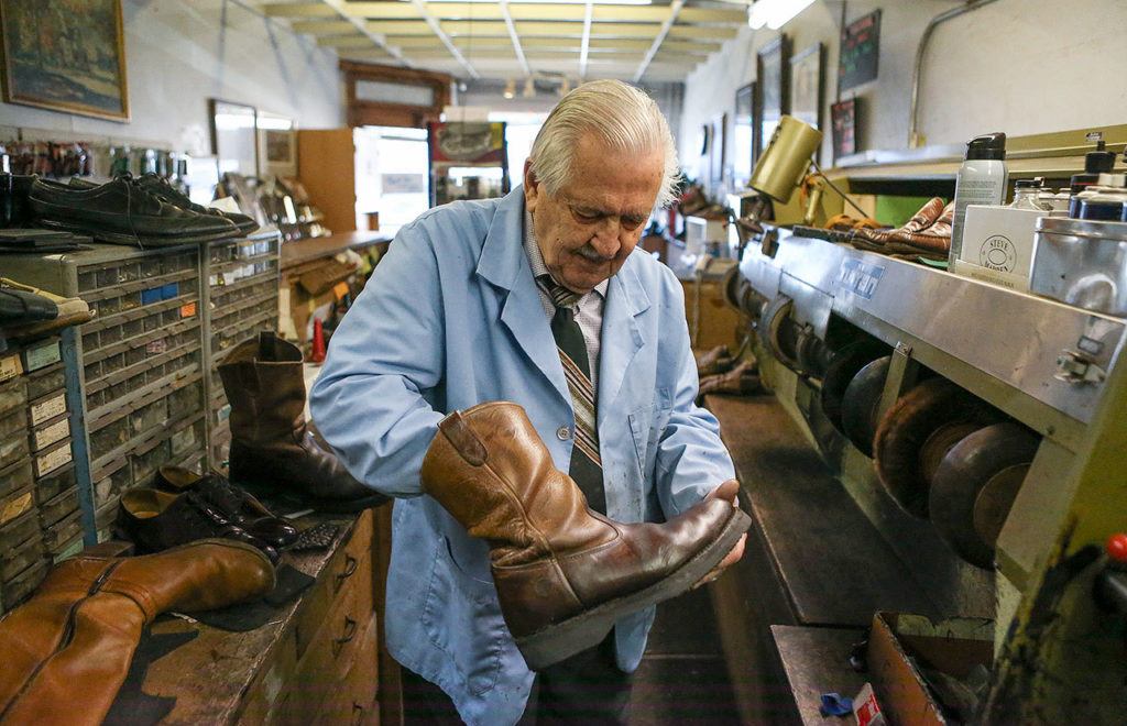 Mike Papadimitriou, owner of People’s Shoe Repair, looks over a boot after buffing it on Jan. 5 in Everett. (Andy Bronson / The Herald)
