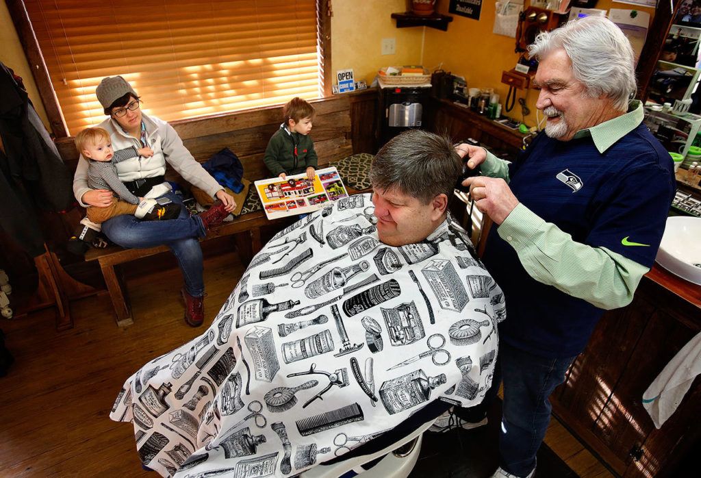 Regular customer Tamara Stramel waits to get her two boys haircuts after Don Baird, 76, finishes with Rick Duell’s hair Friday at his Silver Lake area shop called Rusty Cuts Barbershop. Baird built the shop using some nice, old barnwood, so when he had a pile of it left over, he decided to build the political statement out back with the lumber. (Dan Bates / The Herald)
