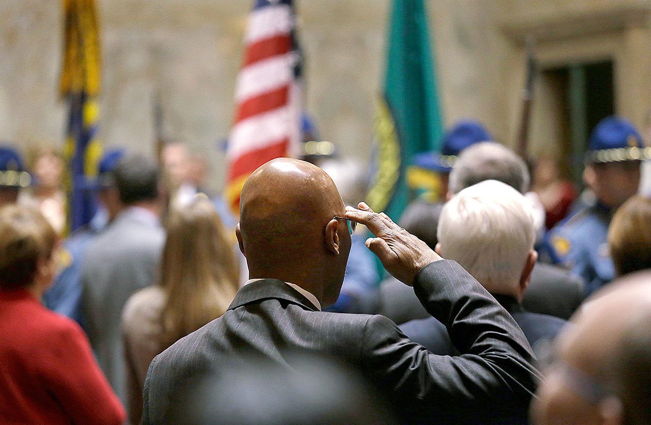 Rep. John Lovick, D-Mill Creek, salutes the flag carried by an honor guard at a joint session of the Legislature on Wednesday, Jan. 11, in Olympia. (AP Photo/Elaine Thompson)