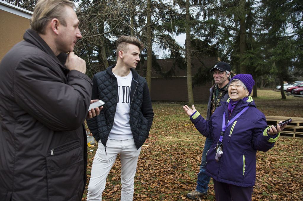 The Rev. Jean Kim (right) smiles while talking with Vitaliy Musiyenko, David Musiyenko and Tony Thompson at the new homeless students living site at Good Shepherd Baptist Church on Jan. 17, in Lynnwood. Kim has devoted her life to helping the homeless and said she hopes to keep adding tents to house more student residents. (Daniella Beccaria / The Herald)
