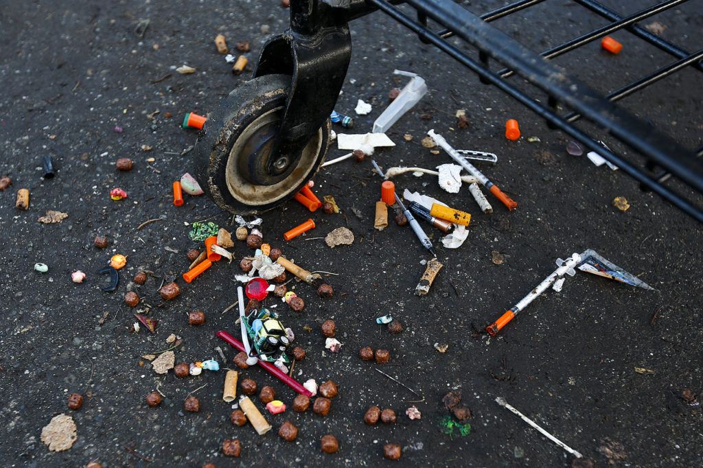 Hypodermic needles litter the driveway of a home in Everett used by squatters. (Ian Terry / The Herald)
