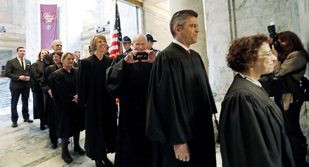 Justice Charles Wiggins (third right) playfully takes a photo as he begins to head into the House chambers for a joint session of the Legislature on Wednesday, Jan. 11, in Olympia. (AP Photo/Elaine Thompson)
