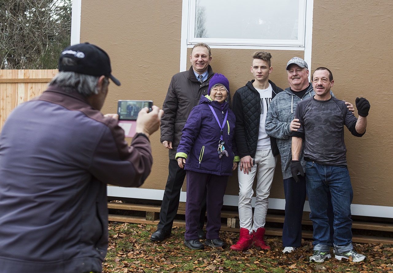 Tony Thompson snaps a group photo of (from left) Vitaliy Musiyenko, Reverend Jean Kim, David Musiyenko, Darrel Potter and Gary Michaels after they completed installing the community living room at the new tent village for homeless students at Good Shepherd Baptist Church on Jan. 17 in Lynnwood. (Daniella Beccaria / The Herald)
