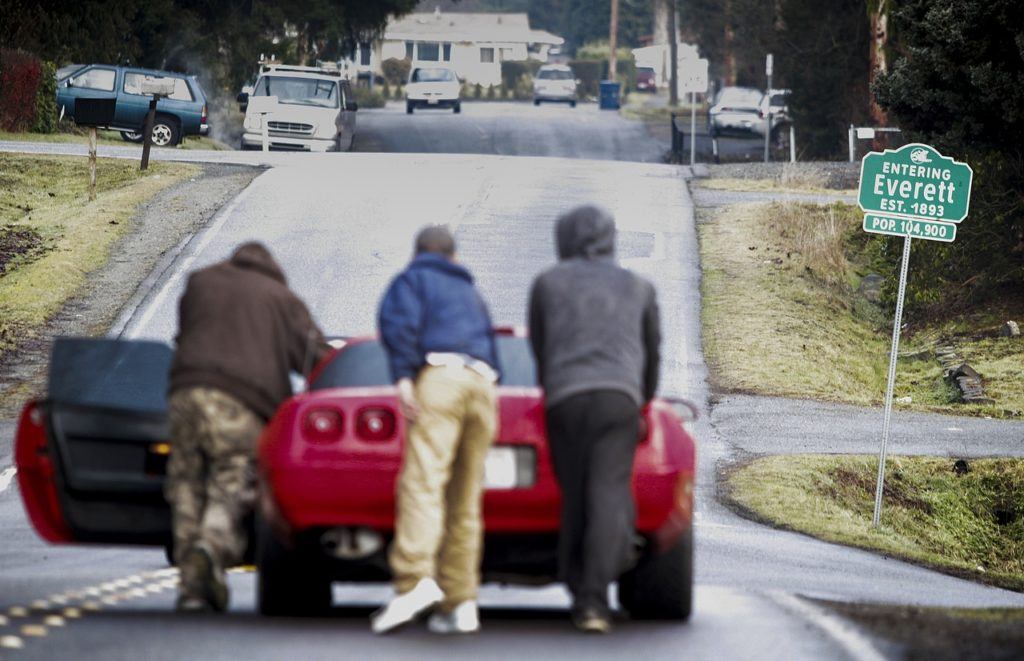 Men evicted from a home filled with squatters push a Chevrolet Corvette down 2nd Avenue SE in Everett on Thursday, Jan. 26. (Ian Terry / The Herald)
