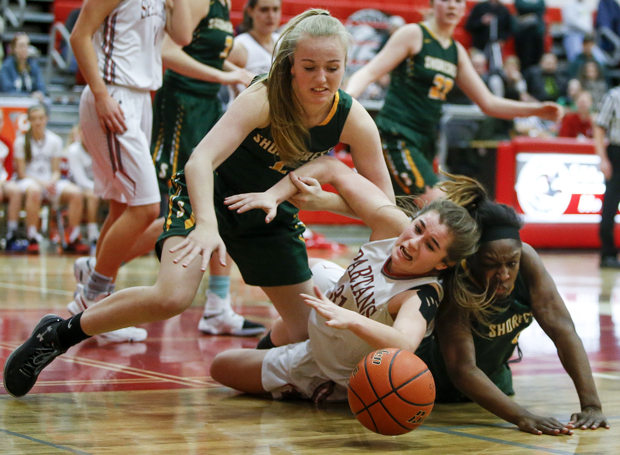 Stanwood’s Madison Chisman (center) dives for a loose ball between Shorecrest’s Audrey Dietz (left) and Jazlyn Owens (right) during a 3A district playoff game Feb. 10, 2017, at Stanwood High School. (Ian Terry / The Herald)