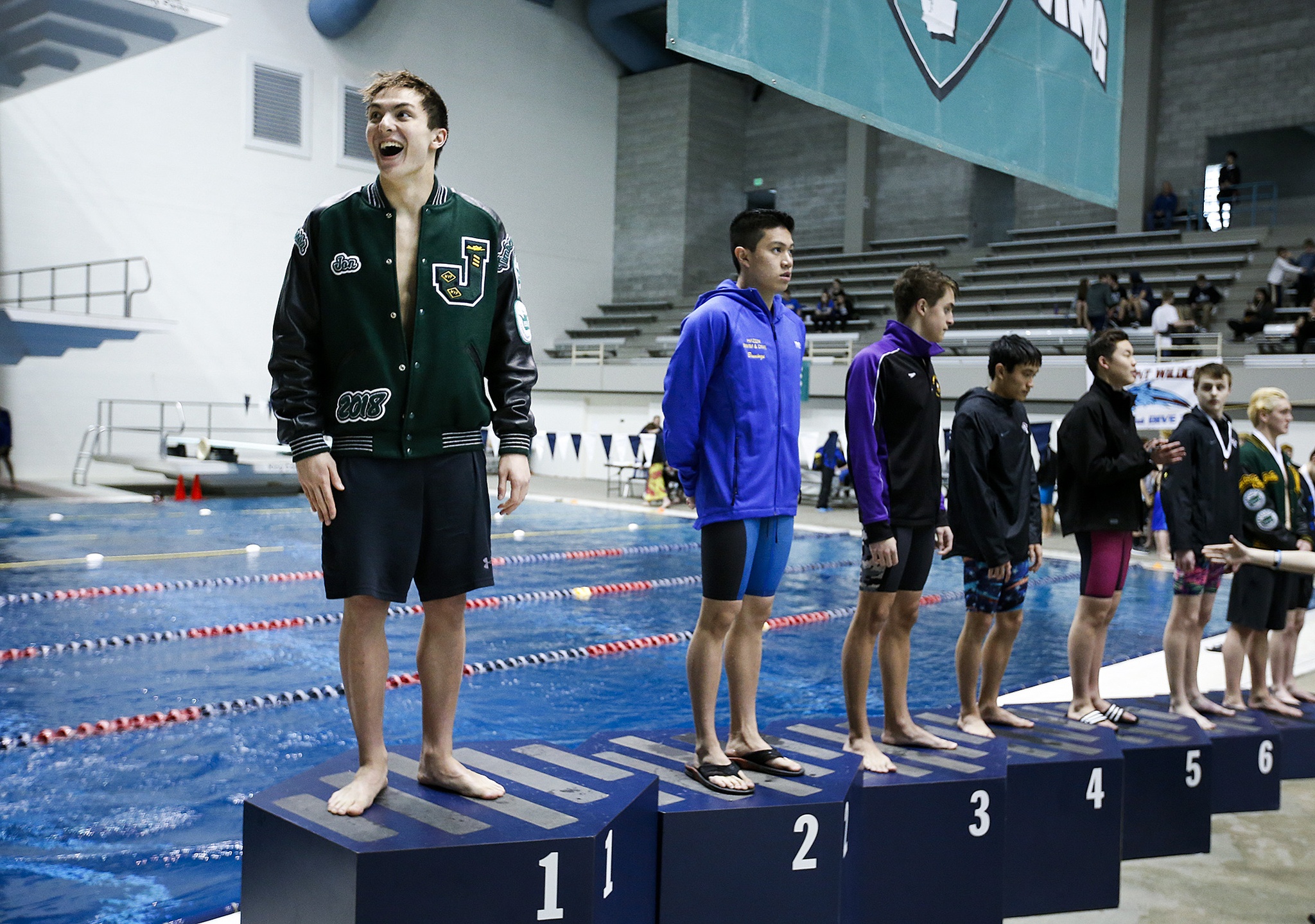Jackson’s Jonathan Cook (left) smiles from the podium after winning the 100-yard breaststroke race at the 4A State Boys Swimming and Diving Championship at the King County Aquatic Center in Federal Way on Feb. 18, 2017. Cook’s time of 53.91 set a meet record. (Ian Terry / The Herald)