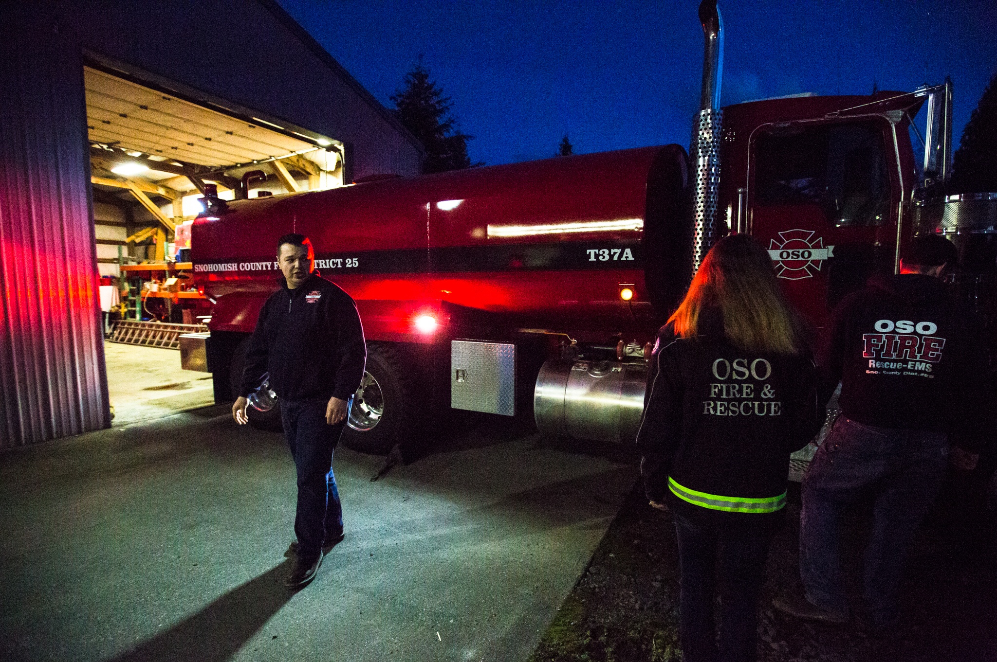 Oso firefighter and chaplain Joel Johnson and firefighters Cyndy Olson and Bill Reynolds inspect the newly repaired firetruck at the Oso fire station on Tuesday, Feb. 21. (Daniella Beccaria / The Herald)