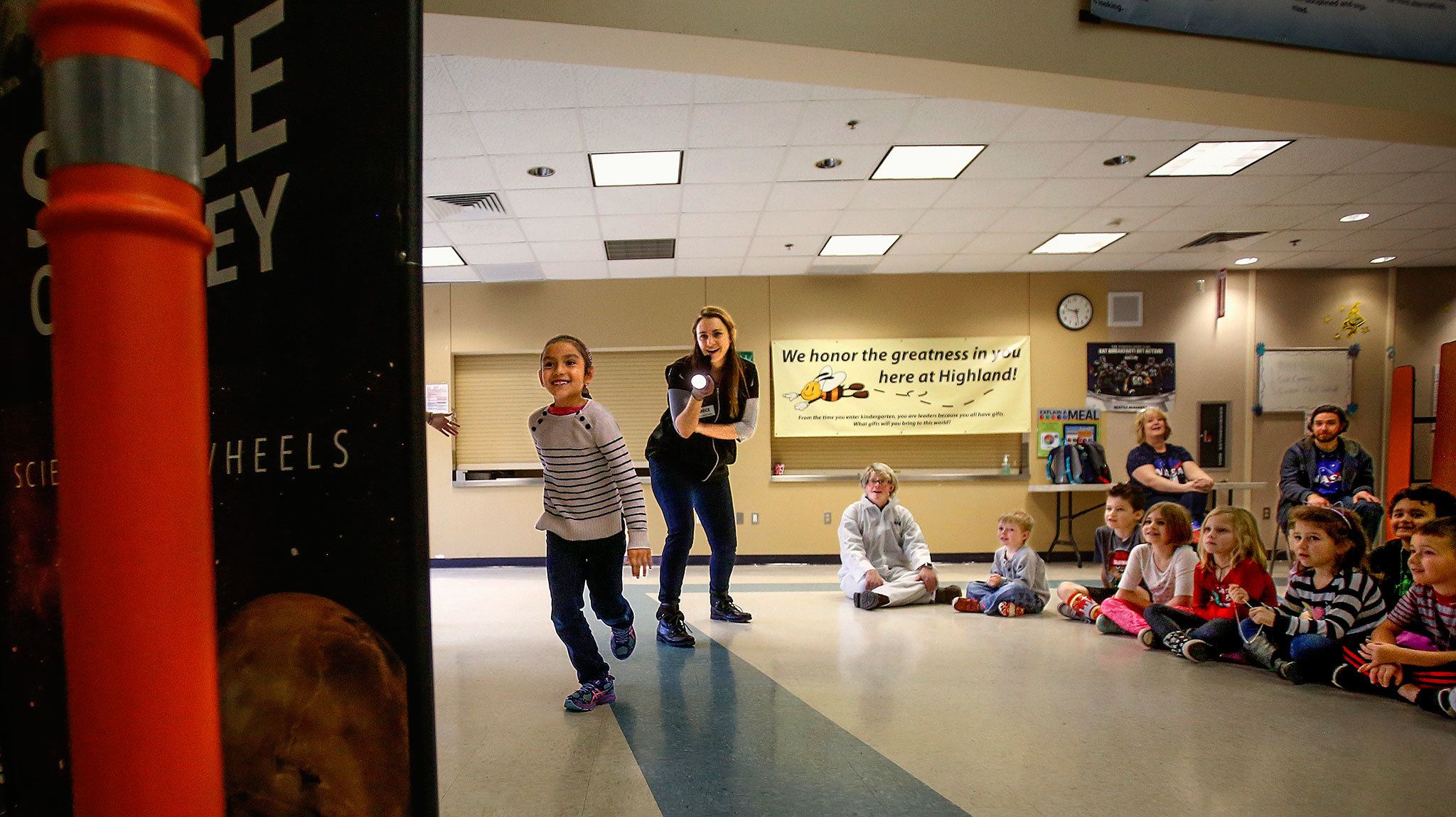 In a game demonstrating the speed of light, Highland Elementary first-grader Ava Aguero tries her hardest to outrun light from a flashlight held by Janice Crew of the Pacific Science Center during a “space” presentation Thursday at the school. (Dan Bates / The Herald)